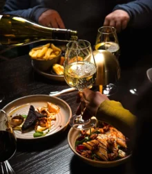 Group dining with wine, gourmet dishes, and warm lighting