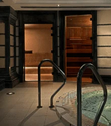 Family enjoying warm spa area with hot tub, sauna and ambient lantern lighting, luxury hotel wellness space