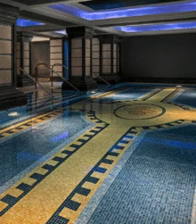 Family enjoying a luxurious indoor mosaic-tiled pool in a calm hotel spa with blue lighting