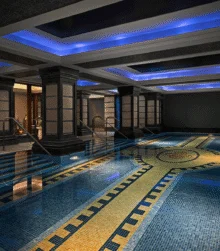 Family enjoying a tranquil indoor hotel pool with mosaic tiles and soft blue ceiling lights