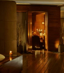 Family enjoying a candlelit spa treatment in a warm wood‑panelled hotel wellness room, soft lighting