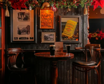 Cosy pub corner with vintage decor and two pints on a wooden table, festive atmosphere.