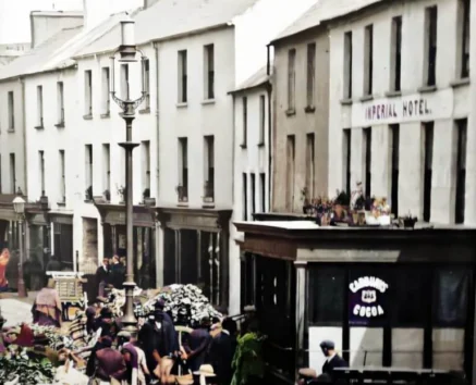Historic street scene with families and shops, outside the Imperial Hotel.