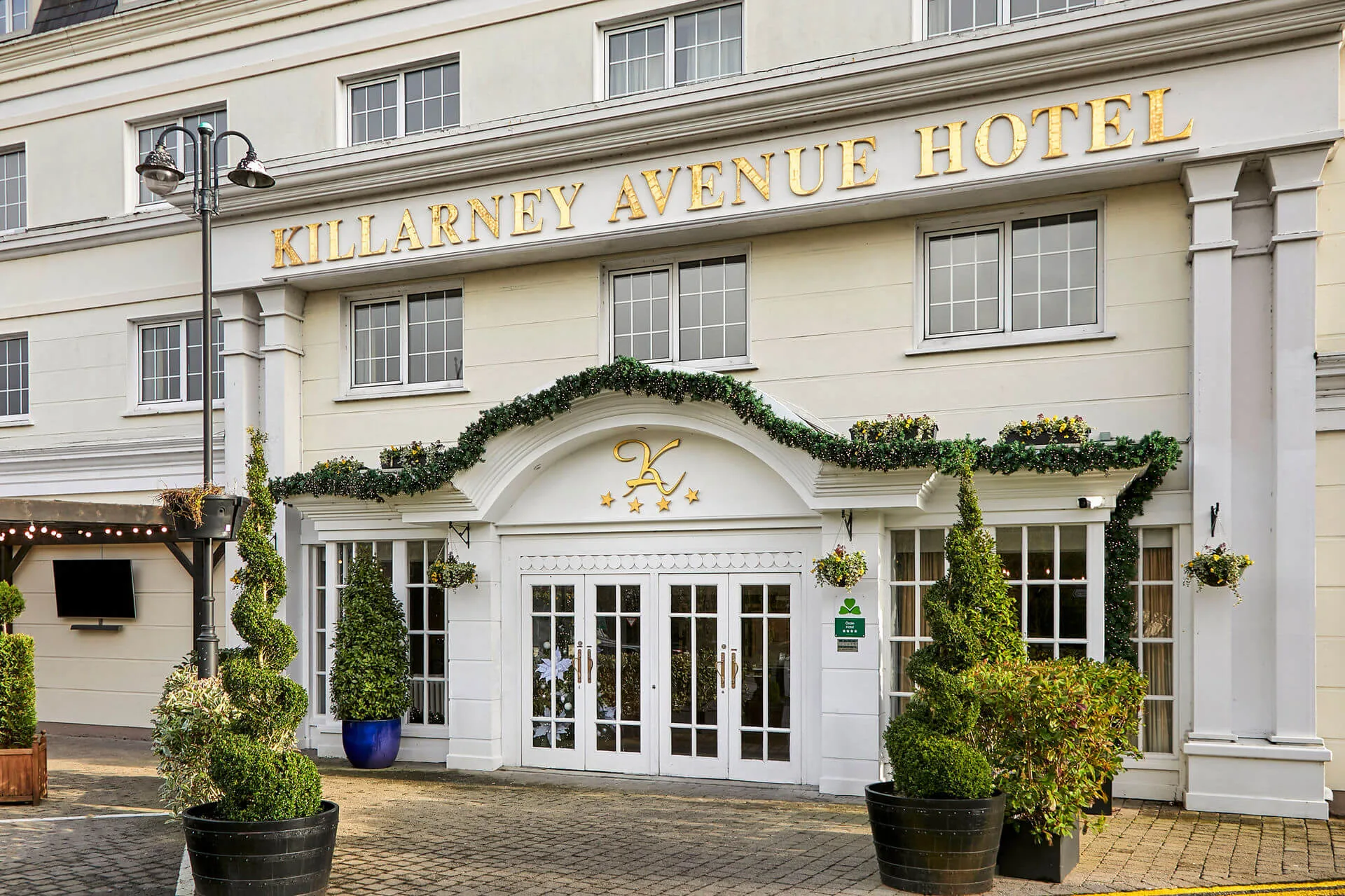 Elegant entrance of Killarney Avenue Hotel with festive greenery.