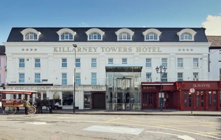 Killarney Towers Hotel exterior with people enjoying the sunny street.