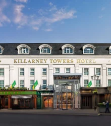 Elegant exterior of Killarney Towers Hotel, inviting entrance under a blue sky.