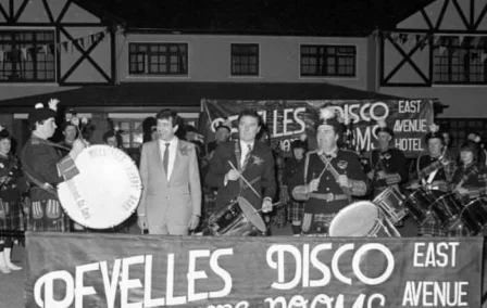 A group of musicians and a man in front of a hotel, enjoying live music.