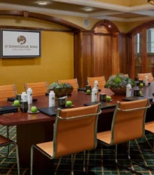 Elegant meeting room setup with a long wooden table, leather chairs, and O'Donoghue Ring Collection branding.