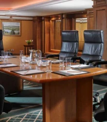 Elegant conference room with leather chairs and large table set for a meeting.
