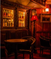 Cosy warmly-lit pub with wooden decor and leather chairs, inviting atmosphere for relaxation.