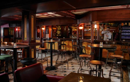 Warm family-friendly pub interior with bartender pouring drinks, cosy wooden seating (Allora CMS)